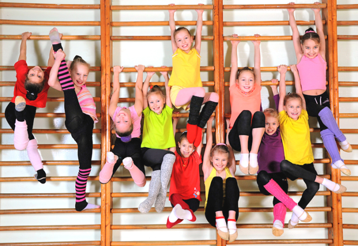 Kinder hängen an einer Sprossenwand in der Turnhalle